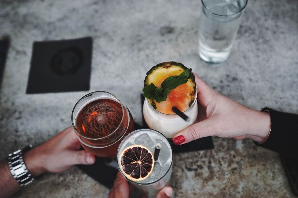 Close-up hands holding cocktails over a table